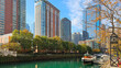a beautiful autumn landscape along the Ogden Slip waterway with boats docked on the green water, autumn colored trees and skyscrapers in the skyline in Chicago Illinois USA