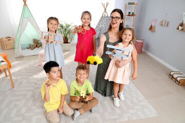 Canvas Print - Little children and nursery teacher with toys in kindergarten