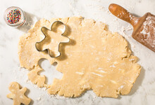 Sugar cookie dough with snowman cookie cutters and rolling pin