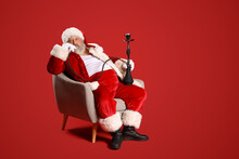 Bad Santa Claus With Hookah Sitting In Armchair On Red Background