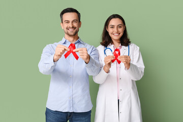 Poster - Handsome adult man and female doctor with red ribbons on green background. World AIDS Day concept