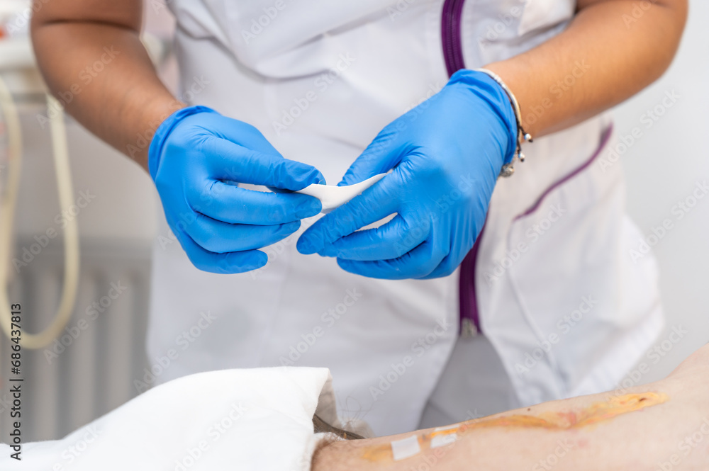 hand of Doctor is using clean cotton dressing infection wound at a man abdomen. Bandage for wound dressing at a clinic. medical care healthcare insurance concept. High quality photo