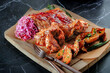 Barbecue wings and ribs on a wooden board with grilled potatoes and sauerkraut