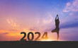 © Peera - New year 2024 fitness healthy woman yoga with sunset sky background