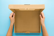 Woman hands holding opened brown carton box on blue table background. Closeup. Empty place for different things, goods, food or products packaging for delivery. Point of view shot. Top down view.