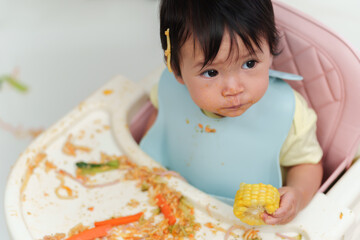 Wall Mural - infant baby eating food and vegetable by self feeding BLW or baby led weaning on chair