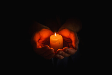 Wall Mural - Religion concept.Concentration time.Remembrance of the dead.burning candle in a mans hand on dark background.