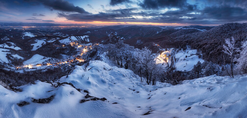 Canvas Print - Panorama of night Carpathian winter mountain village in light with wooden houses on a hill covered with fresh snow.