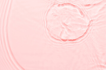Wall Mural - Water pink surface abstract background. Waves and ripples texture of cosmetic aqua moisturizer with bubbles.