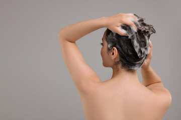 Sticker - Woman washing hair on grey background, back view. Space for text