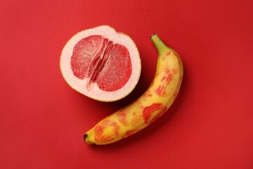 Wall Mural - Banana with lipstick marks and half of grapefruit on red background, flat lay. Sex concept