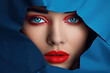 Face of a young beautiful woman with a bright make-up and with plump red lips peeks into a hole in blue paper. Beauty, fashion, personal care, cosmetics, make-up, health, beauty salon, make-up artist.