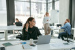 © Kostiantyn - Smiling female entrepreneur working on laptop while sitting in modern coworking and looks away