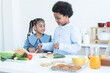 © Pruksachat - African children making sandwich, preparing food in kitchen together at home. Smiling brother and sister pick ham sliced, tomato, zucchini vegetables on top of bread. Orange juice and cookies on table
