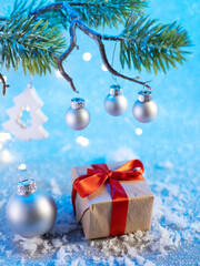 Wall Mural - a gift box with a red ribbon on the Christmas table with artificial snow, a branch of a Christmas tree and silver balls