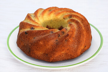 Homemade bundt cake with vanilla, cocoa and raisins on a plate, light background