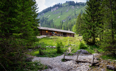 Wall Mural - Mountain landscape. Adventure background. Small wooden cabin with mountain background. Dark building in the woods. Ecological house. Adamello group, Italy.