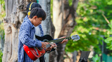 Young Asian Boys Are Playing Acoustic Guitars In Front Of A House, Soft And Selective Focus                              