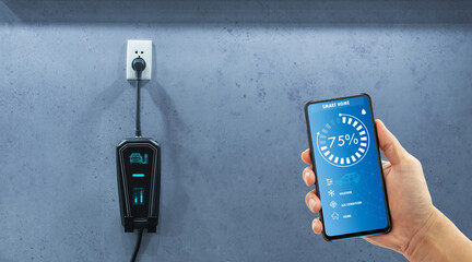 Wall Mural - Using a cable to charge an electric car at home while using a mobile app