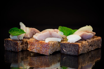 Sticker - canape of pieces of salted herring with onions on a fresh dark piece of bread.