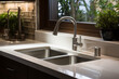 A sleek and modern kitchen setting featuring a stainless steel undermount sink paired with a high-arc, pull-down faucet. The countertops are of polished granite