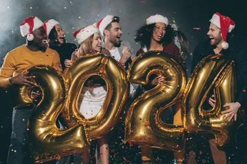 Wall Mural - Happy young friends in Christmas hats celebrating 2024 New Year in night club together