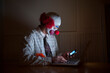© Designpics - Clown wearing a shirt and tie uses a laptop computer and smart phone simultaneously; Lincoln, Nebraska, United States of America