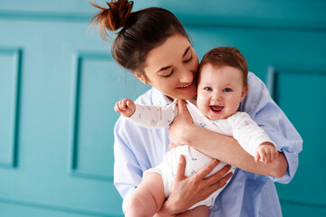 Happy mother carrying her baby at home