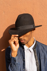 Canvas Print - Stylish young man wearing a hat at a wall