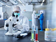 © tunedin - Chemists working in industrial laboratory, wearing protective clothing, using microscope