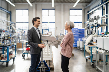 smiling businessman and senior businesswoman talking in a factory