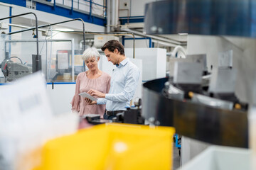 Sticker - Businessman and senior woman with tablet talking in a factory