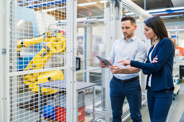 Sticker - Businessman and businesswoman with tablet talking in modern factory