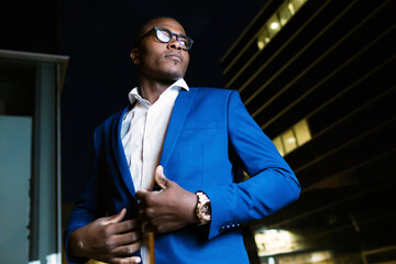 Wall Mural - Young businessman wearing blue suit jacket, ooking sideways at night