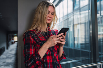 Young woman in modern office building looking at cell phone