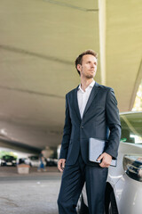 Poster - Businessman standing next to car holding laptop