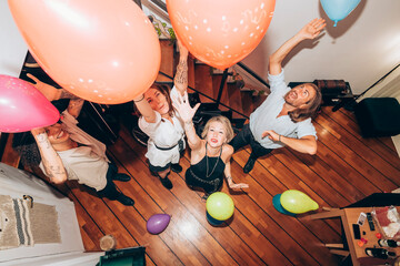 Wall Mural - Cheerful friends dancing with colorful balloons during party at home