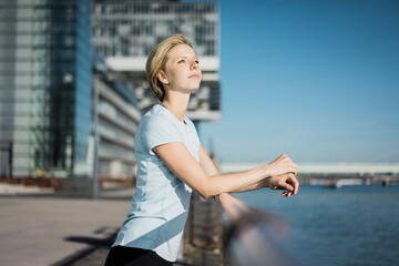 Young woman standing at the riverside, enjoying the sun