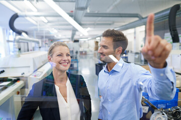 Sticker - Young male technician pointing at graphical interface on glass in factory