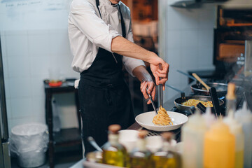 Chef preparing a pasta dish in traditional Italian restaurant kitchen