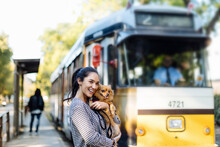 Happy Young Woman With Dog At Tram Station In The City