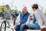 Fototapeta  - Senior man and adult grandson talking on a bench