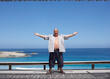 © Designpics - Man Standing by the Beach, Arms Raised in the Air