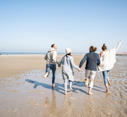 Wall Mural - Playful family holding hands while running at beach