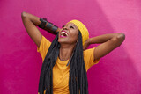 Fototapeta  - Portrait of woman with long dreadlocks laughing in front of a pink wall