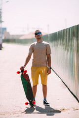 Wall Mural - Portrait of confident young man with longboard