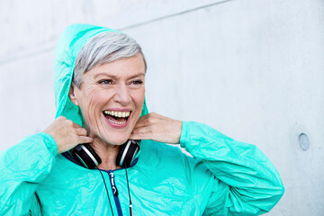 Wall Mural - Portrait of laughing sporty mature woman with headphones