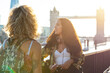 UK, London, two friends together in the city with Tower Bridge in background at sunset