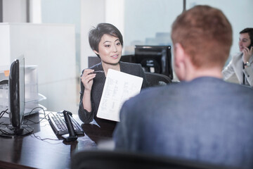 Canvas Print - Woman showing sheet of paper to man at desk in office