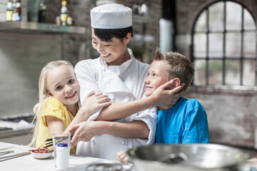 Female chef with happy boy and girl in cooking class